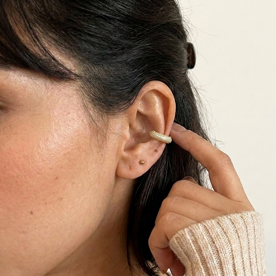 Close-up of a person wearing a gold earring ear cuff