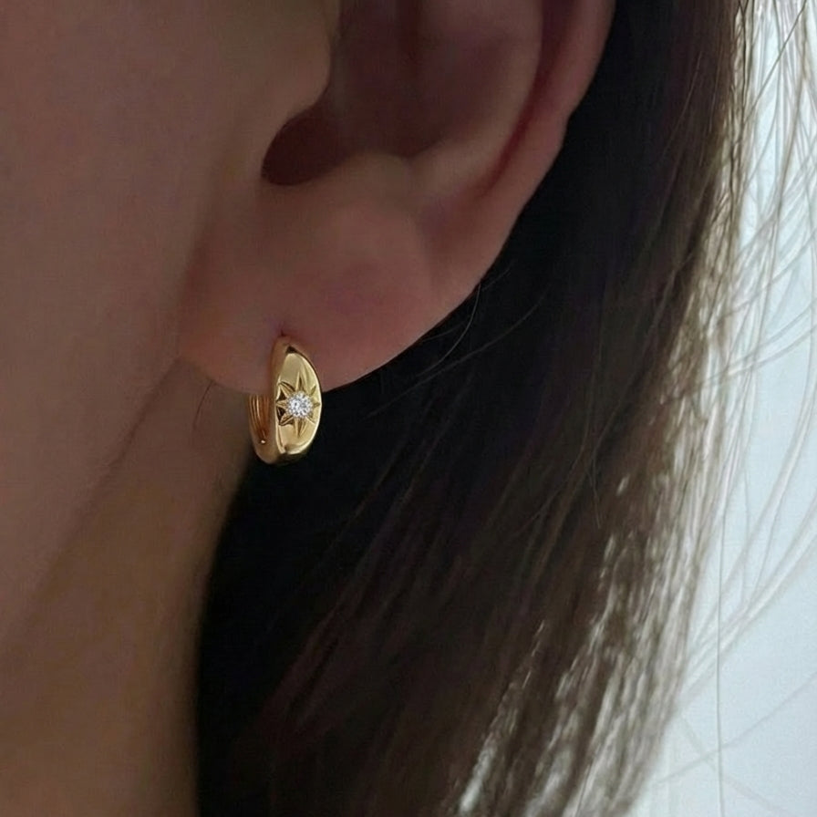 Gold earring worn by a person with a neutral background
