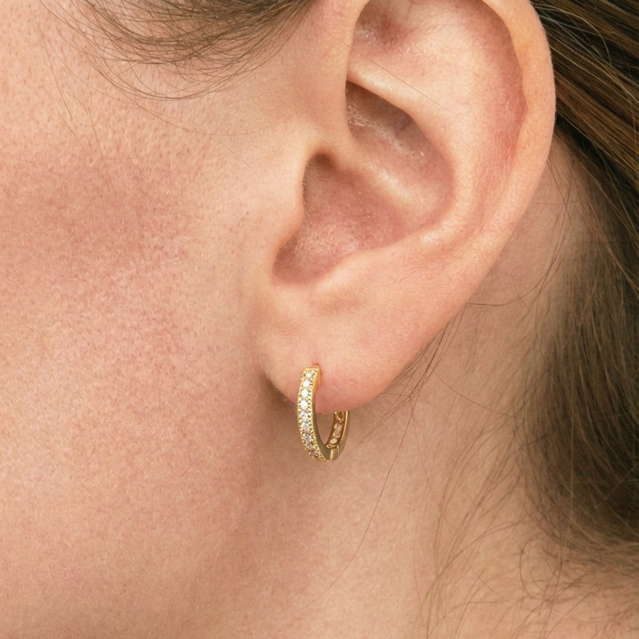 Close-up of an ear wearing a gold hoop earring.